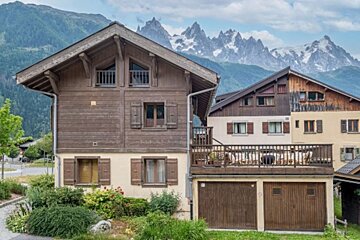 A house with a balcony and mountains in the background