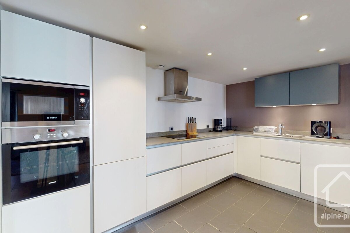 A modern kitchen featuring white and grey cabinets, integrated stainless steel appliances, and sleek countertops.