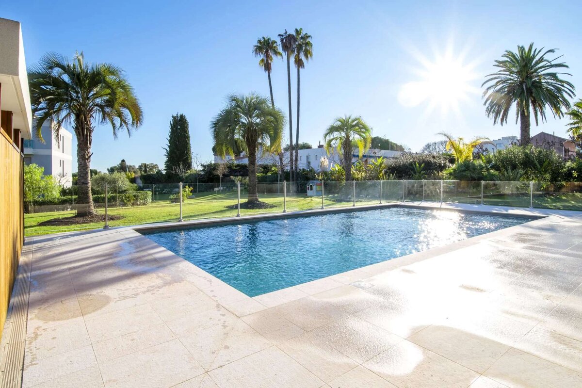 A large swimming pool surrounded by palm trees on a sunny day