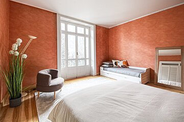 A bedroom with a bed a chair and a mirror