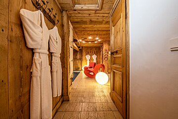 A wooden hallway with white robes and a red chair