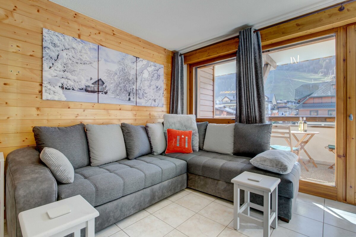 A living room with a large sectional couch and a balcony