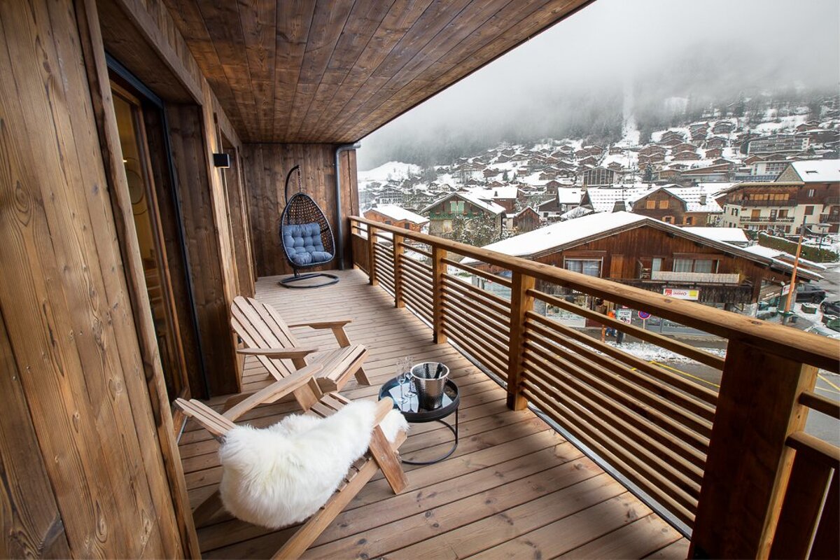 A balcony with two chairs and a table with a bottle of champagne on it