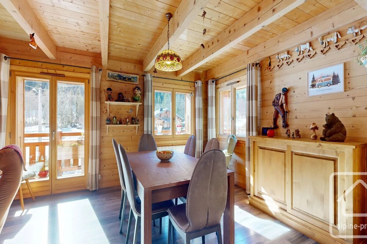 Cozy dining room inside a rustic wooden chalet, featuring a dining table, chairs, and mountain-themed decor.