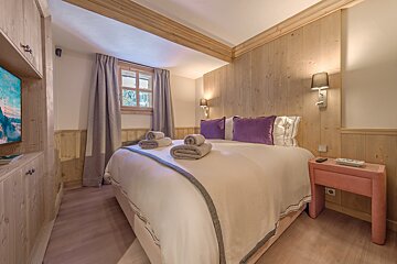 A bedroom with a large bed and purple pillows