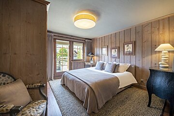 A bedroom with a large bed and two lamps