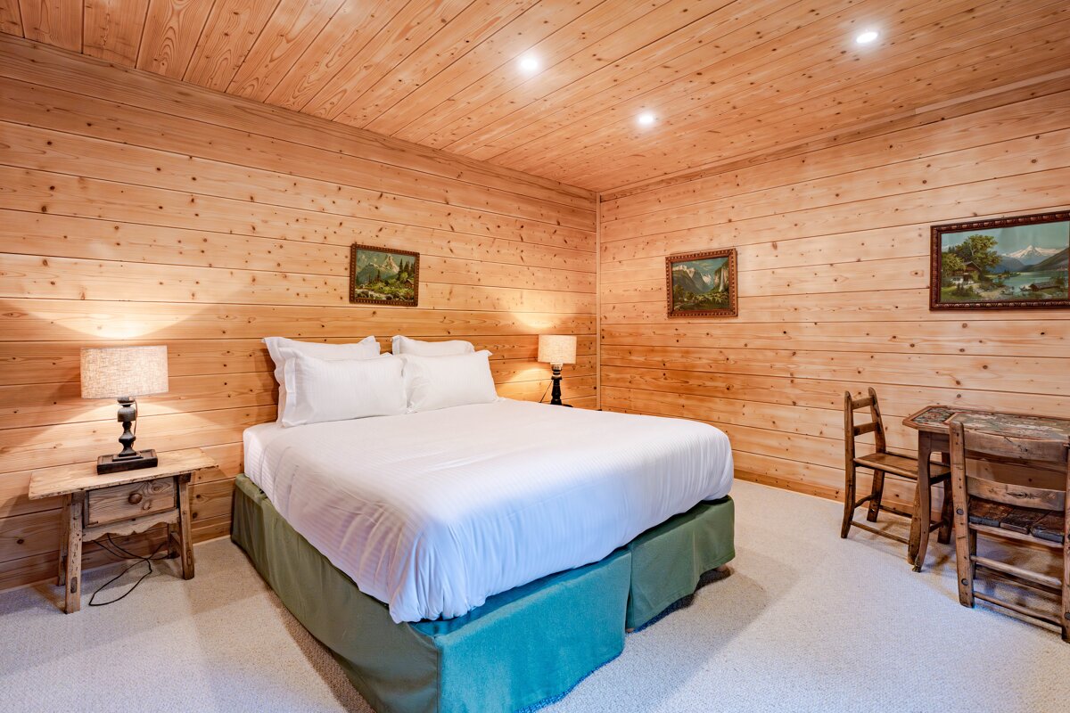 A bedroom with a bed and two paintings on the wall