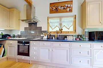 A kitchen with a painting of cows above the window