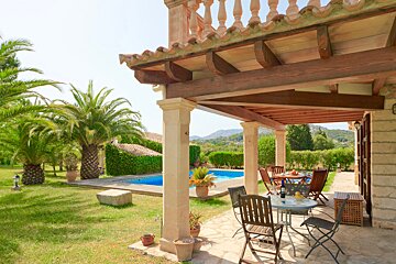 A patio with a table and chairs in front of a pool