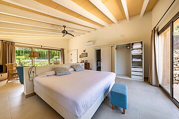 A bedroom with a large bed and a ceiling fan