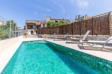 A large swimming pool surrounded by chairs and a fence