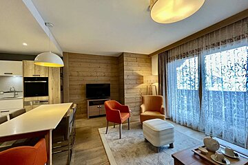 A living room with a table and chairs and a flat screen tv