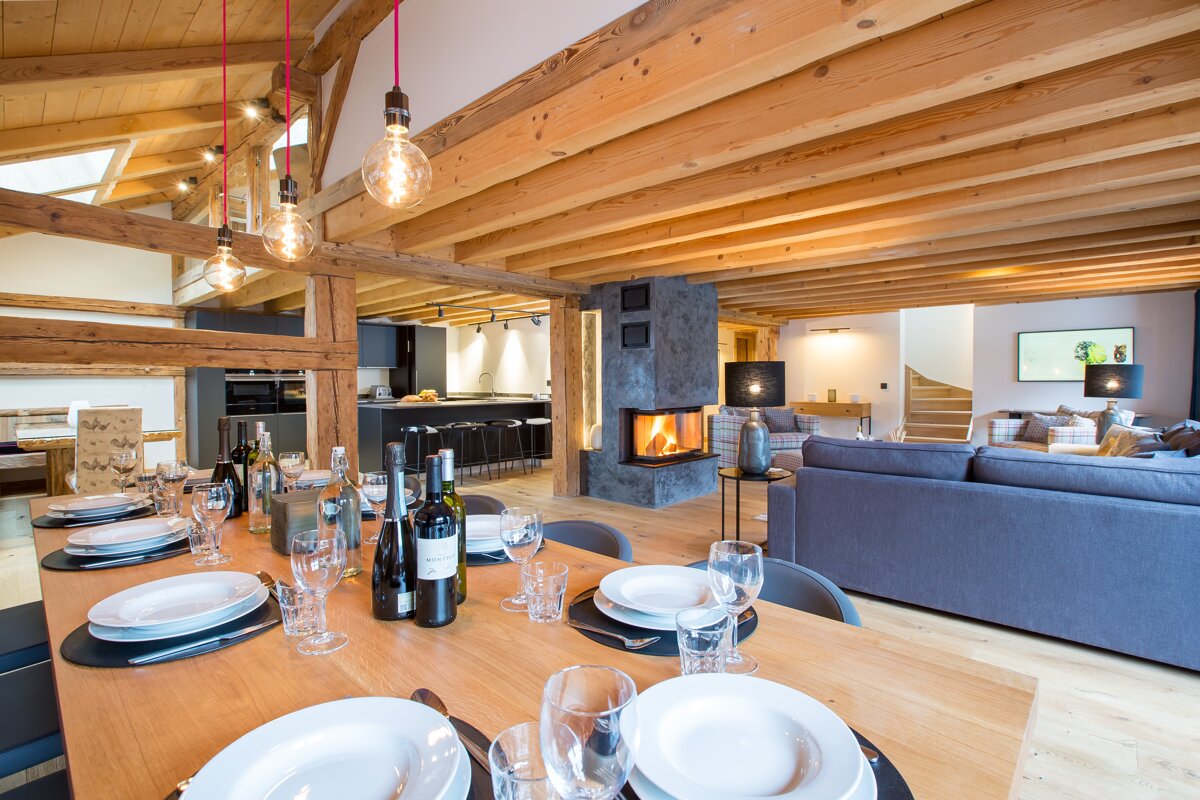 A dining room table with plates and glasses and two bottles of wine on it