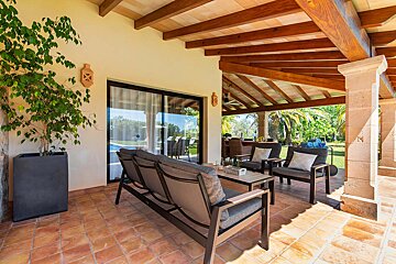 A patio with a couch and chairs under a wooden roof