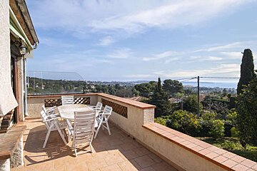A balcony with a table and chairs overlooking the ocean