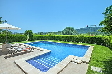 A large swimming pool is surrounded by a lush green lawn