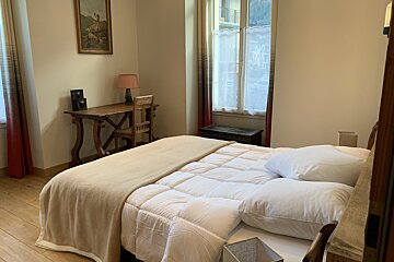 A bedroom with a bed a desk and a lamp