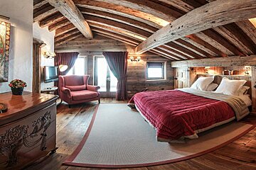 A bedroom with a large bed and a chair