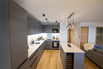 A kitchen with gray cabinets and white counter tops