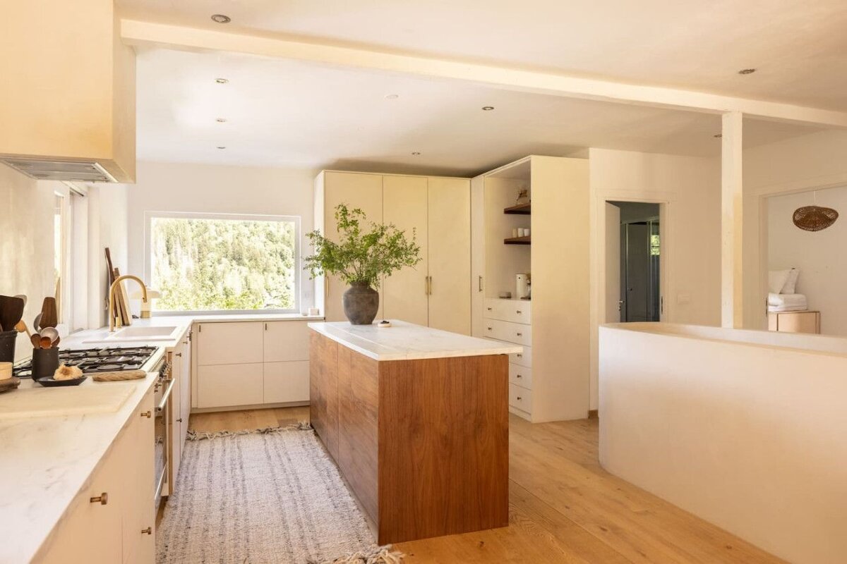 A kitchen with white cabinets and a wooden island