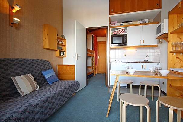 A living room with a couch and a kitchen with a box on the shelf that says ikea