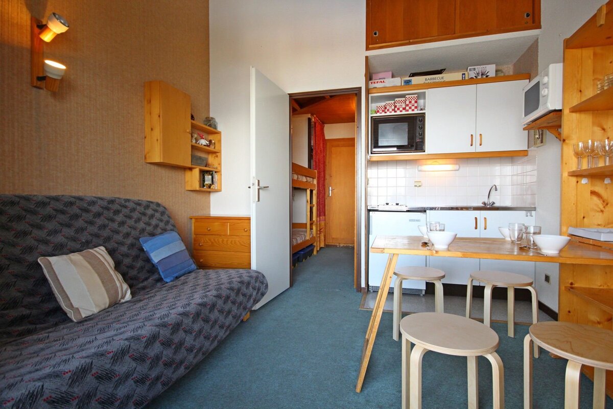 A living room with a couch and a kitchen with a box on the shelf that says ikea
