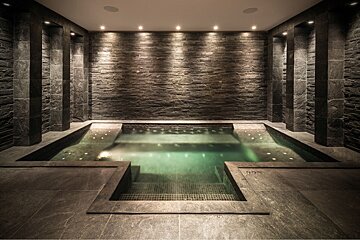 A swimming pool in a dark room with a brick wall
