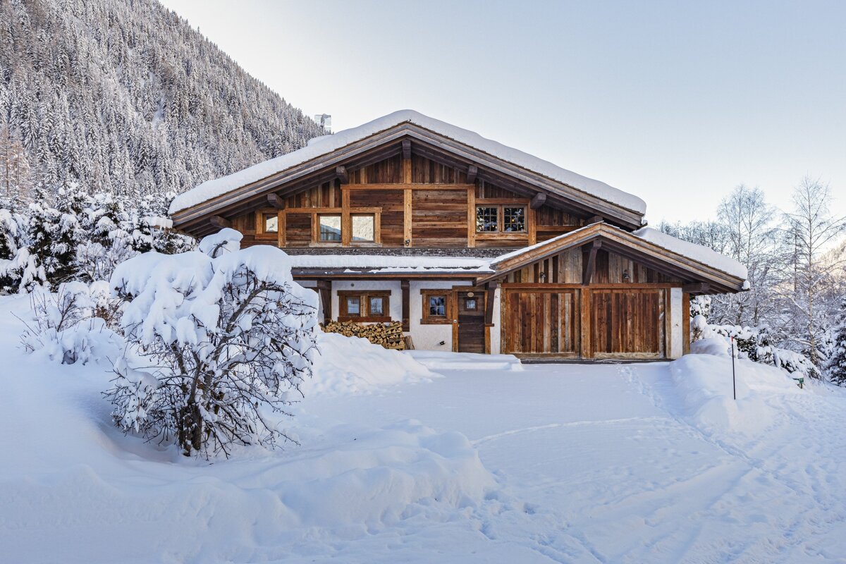 A large wooden house is covered in snow