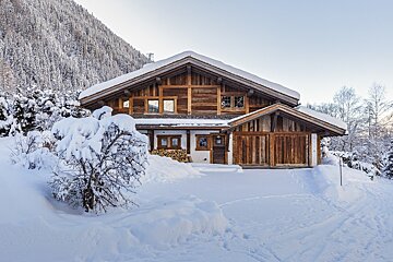 A large wooden house is covered in snow
