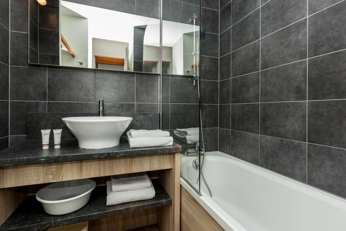 A bathroom with a sink a tub and a mirror
