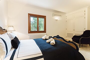 A bedroom with a large bed and a chair