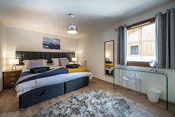 A bedroom with a large bed and a desk