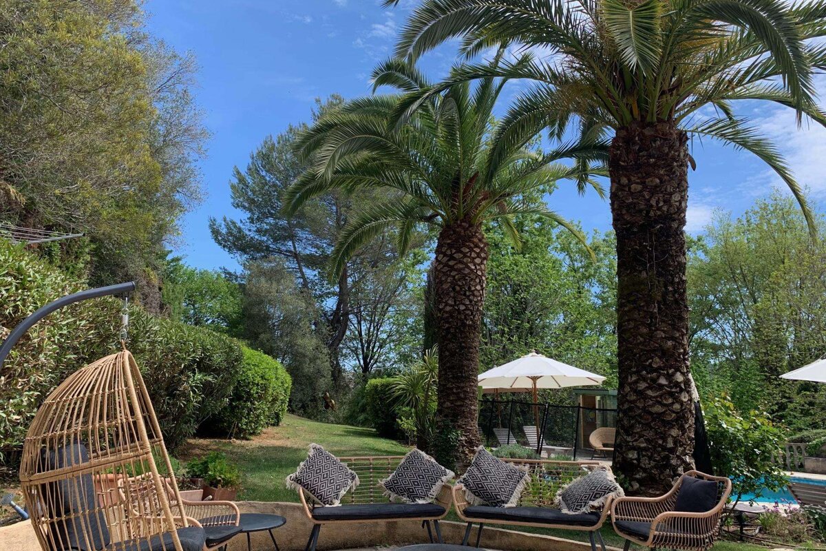A patio area with palm trees and chairs and umbrellas
