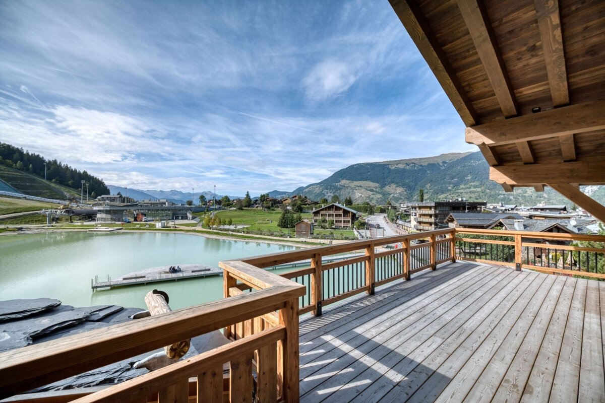 A wooden deck overlooking a lake with mountains in the background