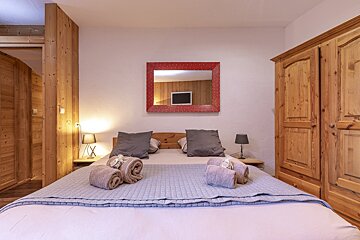 A bedroom with a bed and a red mirror above it