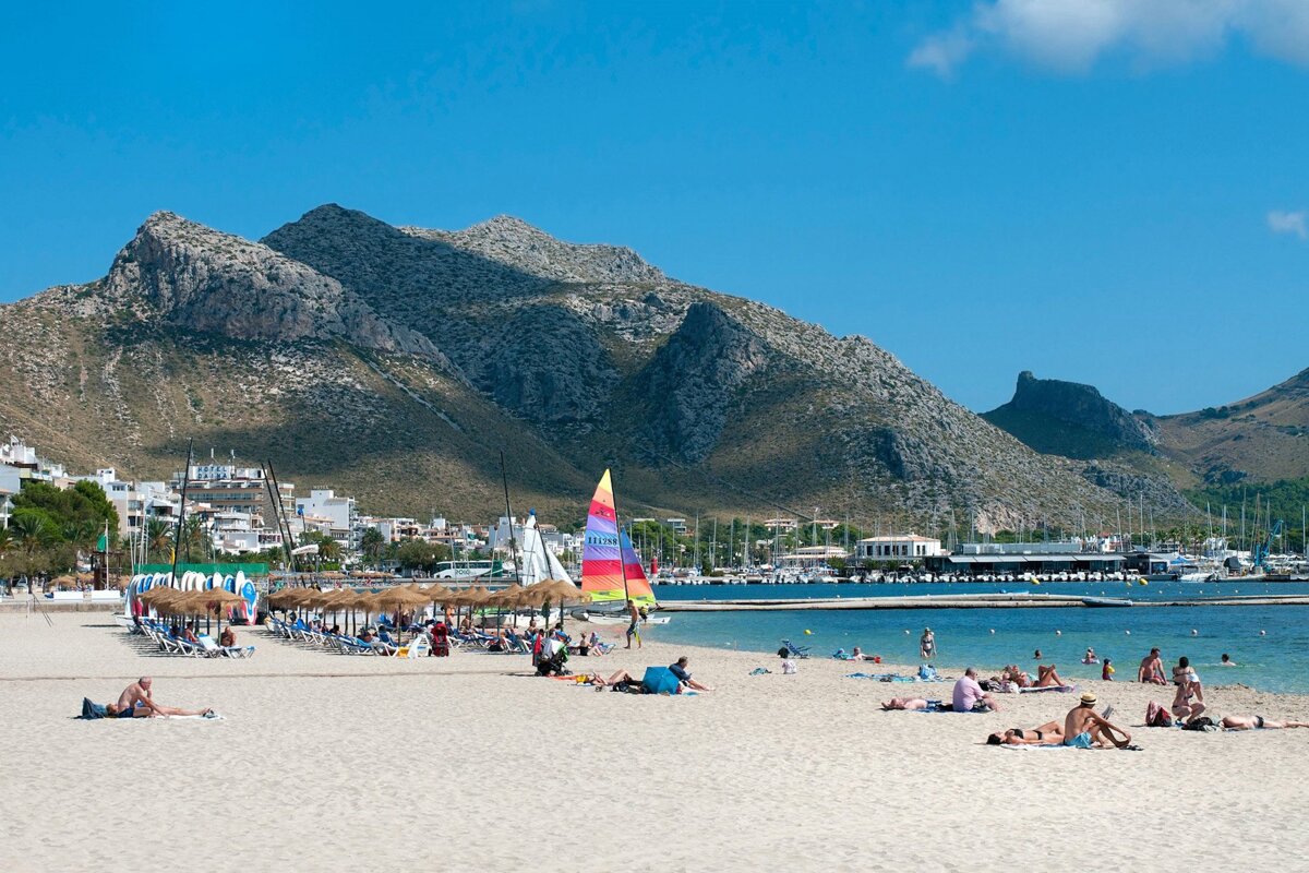 A sailboat on a beach with a mountain in the background