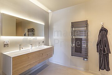 A bathroom with two sinks and a towel rack with the word property on the wall