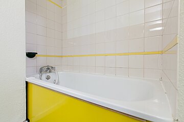 A bathtub in a bathroom with a yellow cabinet