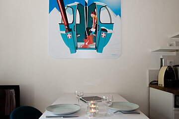 A painting of a ski lift hangs above a dining table