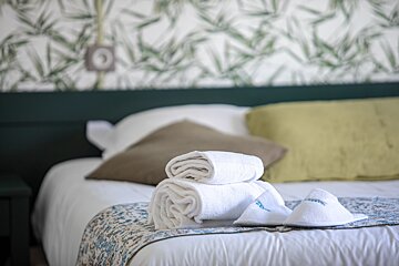 A stack of white towels on a bed with the word hotel on them