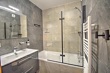 A bathroom with a bathtub a sink and a mirror