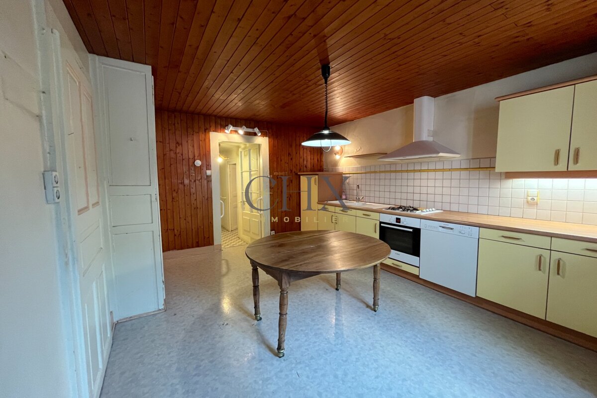 Rustic kitchen featuring a wooden ceiling, a central round wooden table, and light yellow cabinetry.