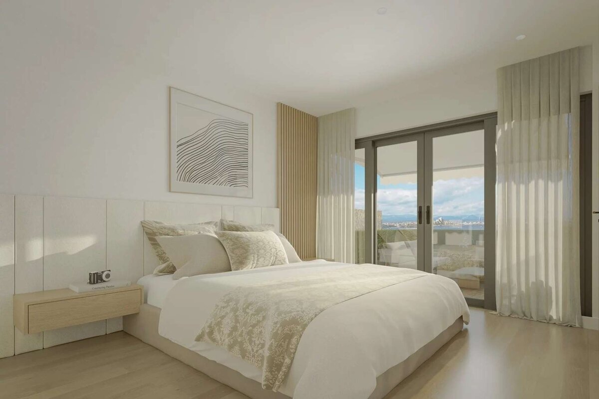 A serene, neutral-toned minimalist bedroom with a large bed, abstract art, and sliding glass doors offering a scenic outdoor view.