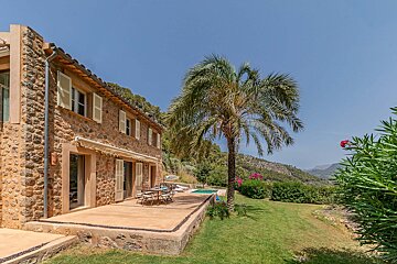 A stone house with a patio and a palm tree in front of it