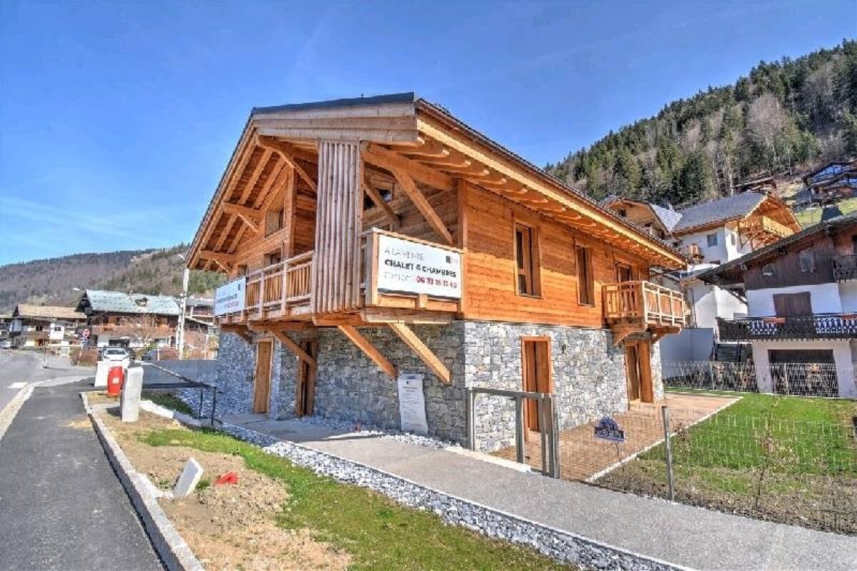 A rustic wooden chalet with a stone base, featuring a 