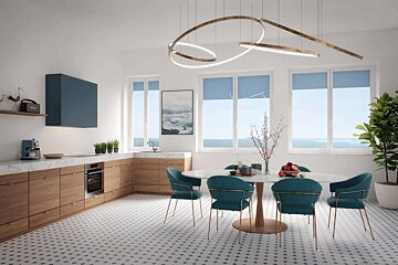 A bright, modern kitchen and dining room with a white and patterned floor. Features wooden cabinets, teal chairs, an ocean view, and a unique chandelier.