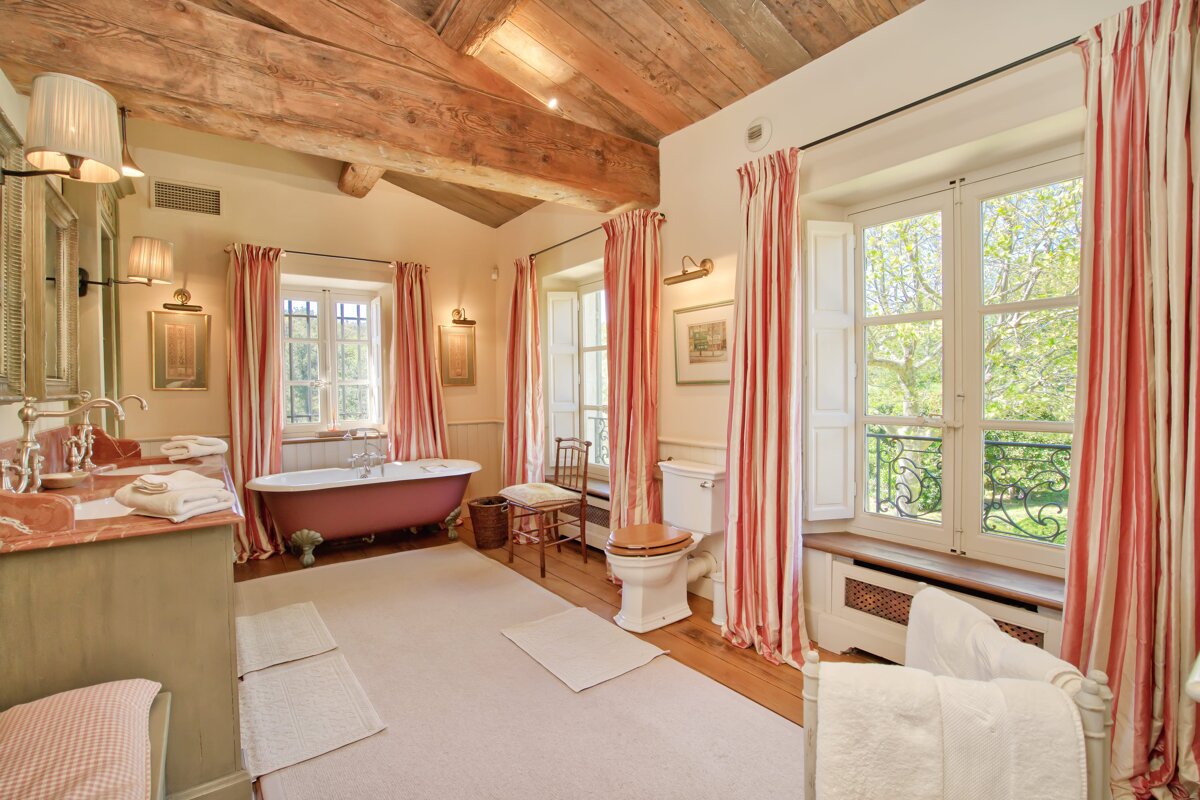 A bathroom with a red tub and striped curtains