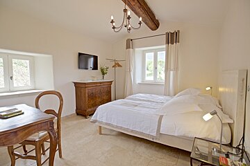 A bedroom with a bed and a television on the wall