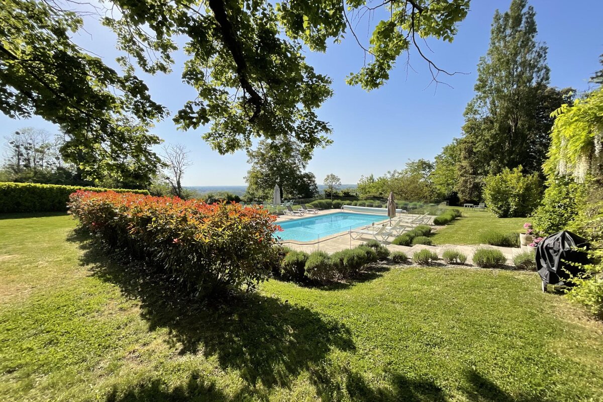 A large swimming pool is surrounded by a lush green lawn