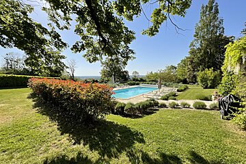 A large swimming pool is surrounded by a lush green lawn